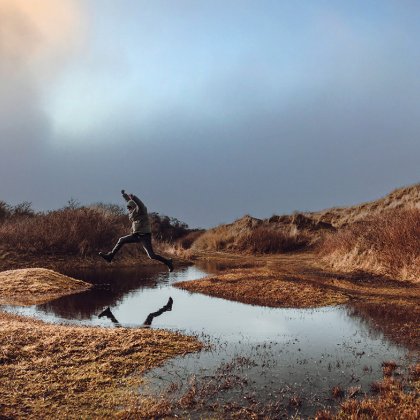 Man jumps over a puddle on Wadden Island Texel