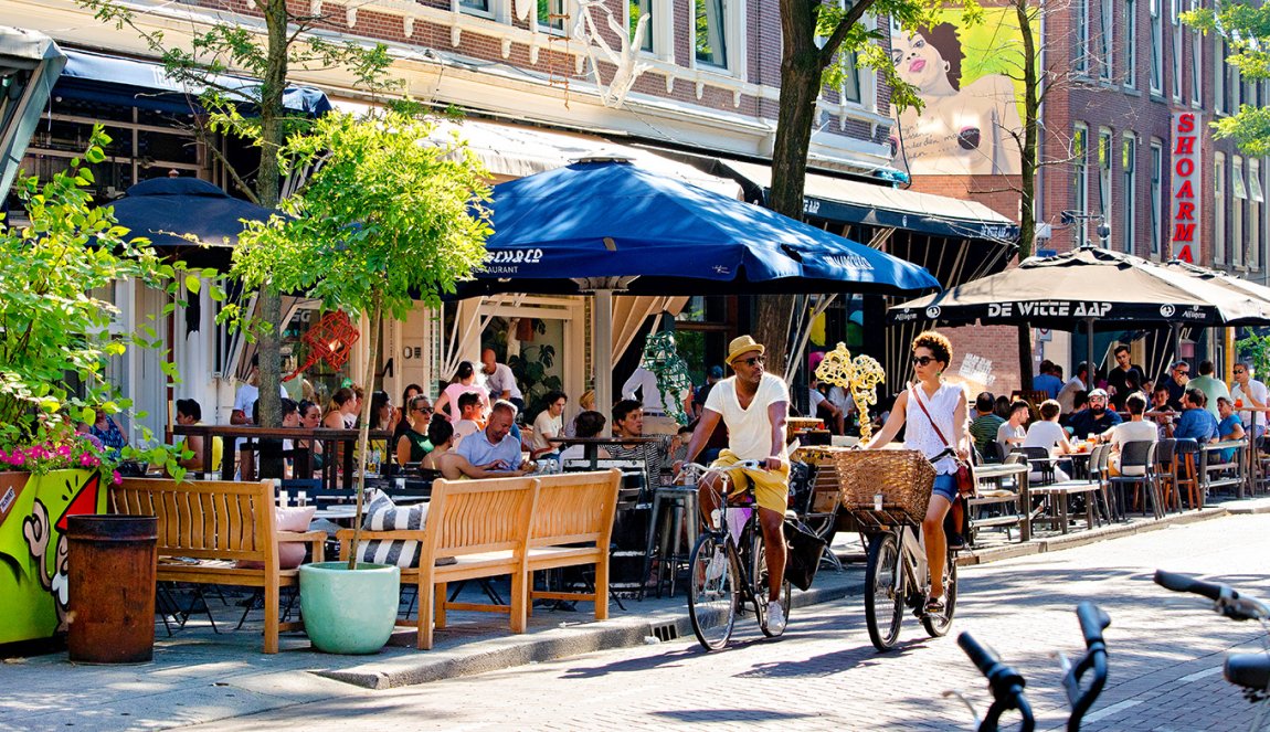 Couple cycling in summer through Witte de Withstraat Rotterdam