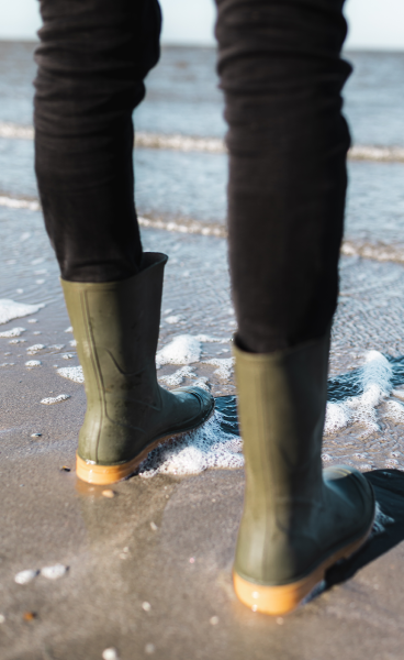 Green rainboots at edge of the sea