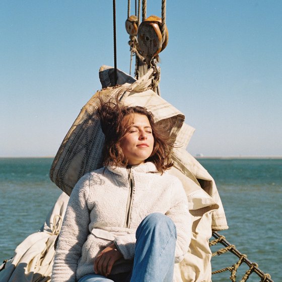 Young woman relaxed in the sun on a sailboat in the Wadden Sea