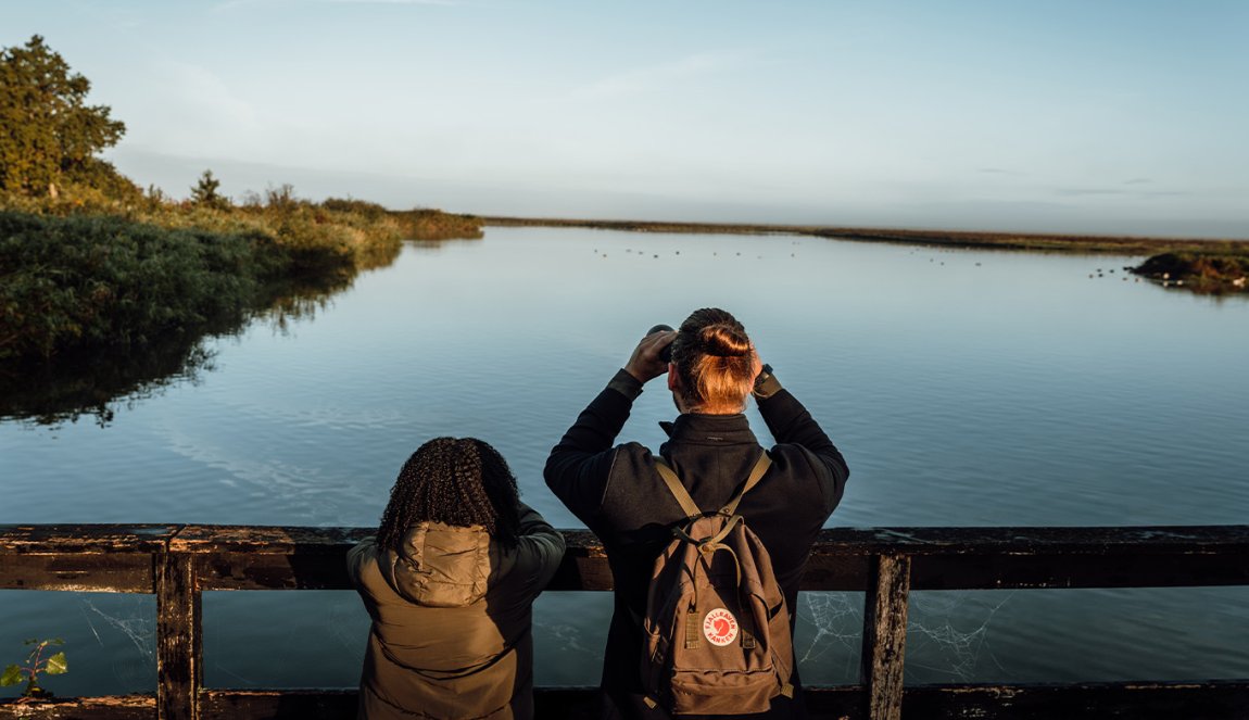 Couple looks over the water with binoculars