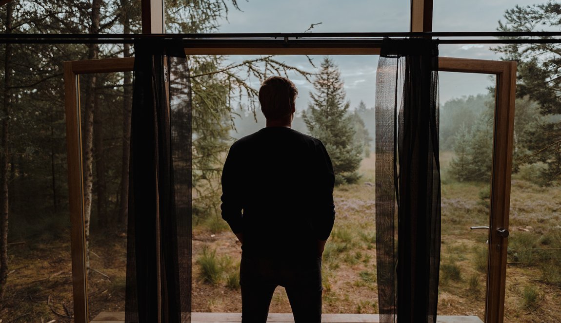 Man looks out of cottage Cabiner in Drenthe 