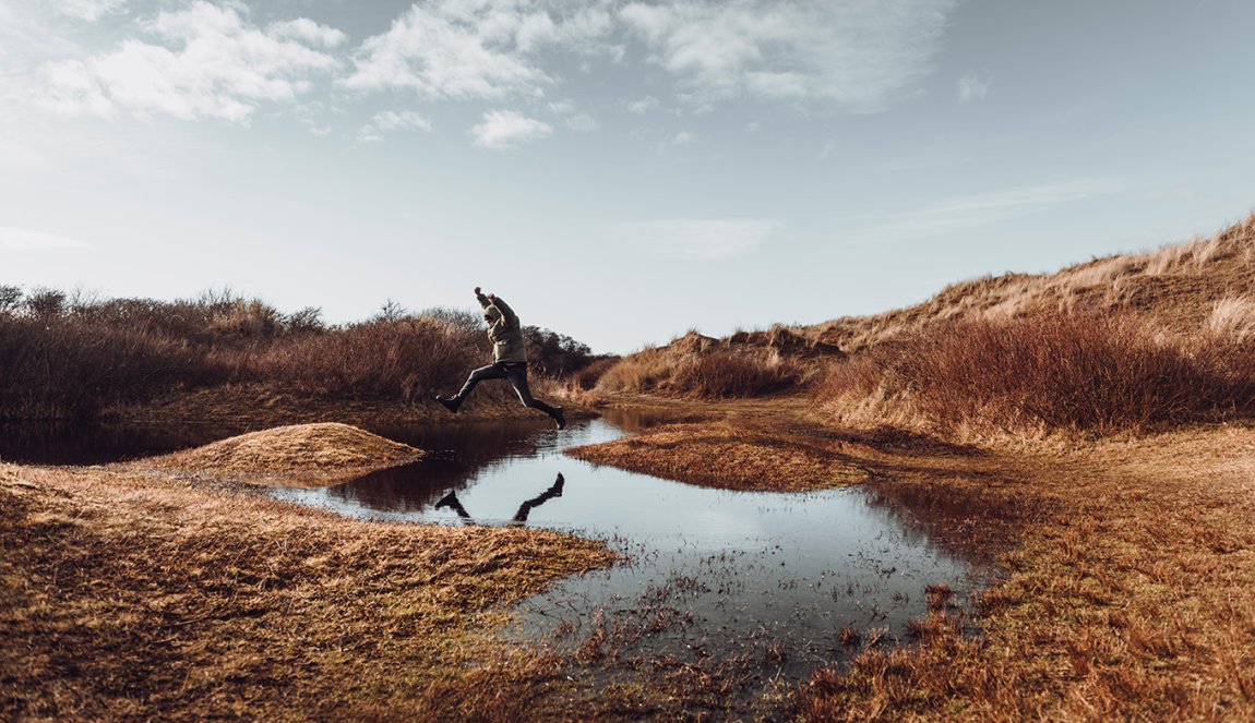 Man jumps over a puddle on Wadden Island Texel