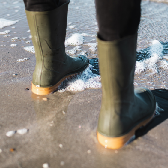 Green rainboots at edge of the sea