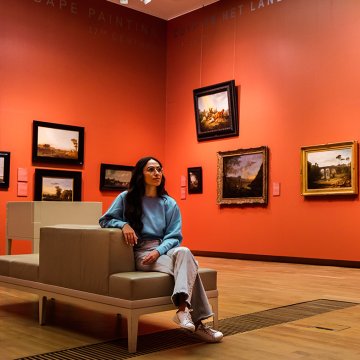 Visitor surrounded by Dutch Golden Age landscape paintings at the Dordrechts Museum in Dordrecht
