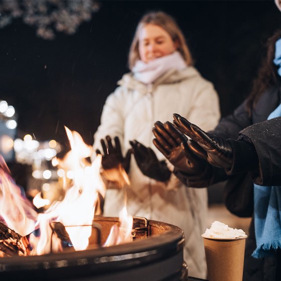 Warm hands by fire with hot chocolate