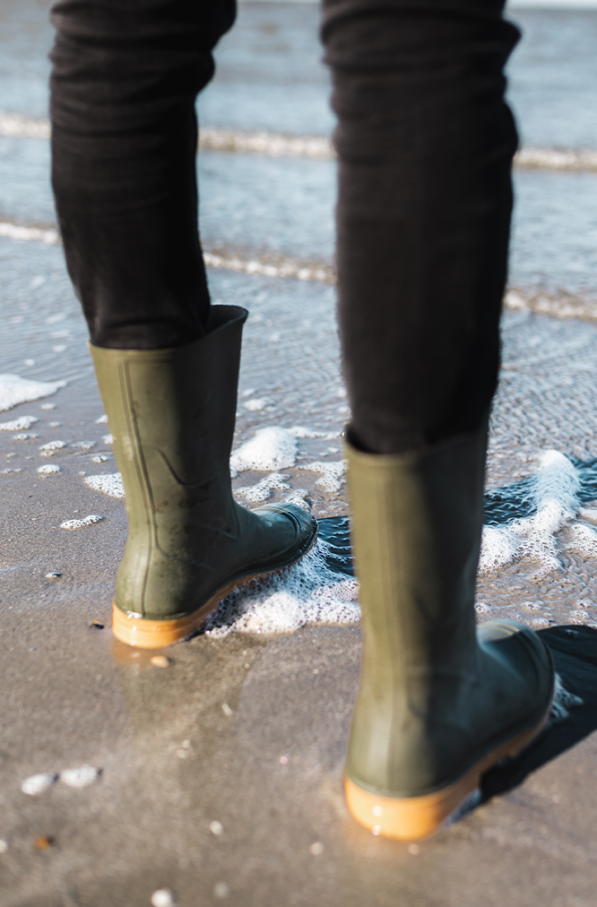 Green rainboots at edge of the sea