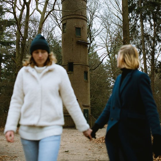 Couple walking hand in hand with the Belvedere Tower Lochemse Berg in the background, Barchem