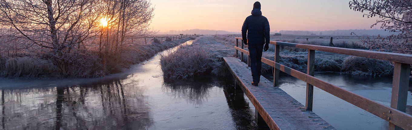 Man walks across footbridge in winter 