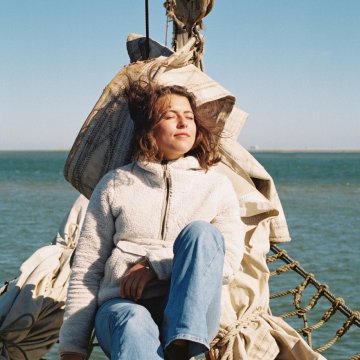 Young woman relaxing in the sun on a sailing boat in the Wadden Sea