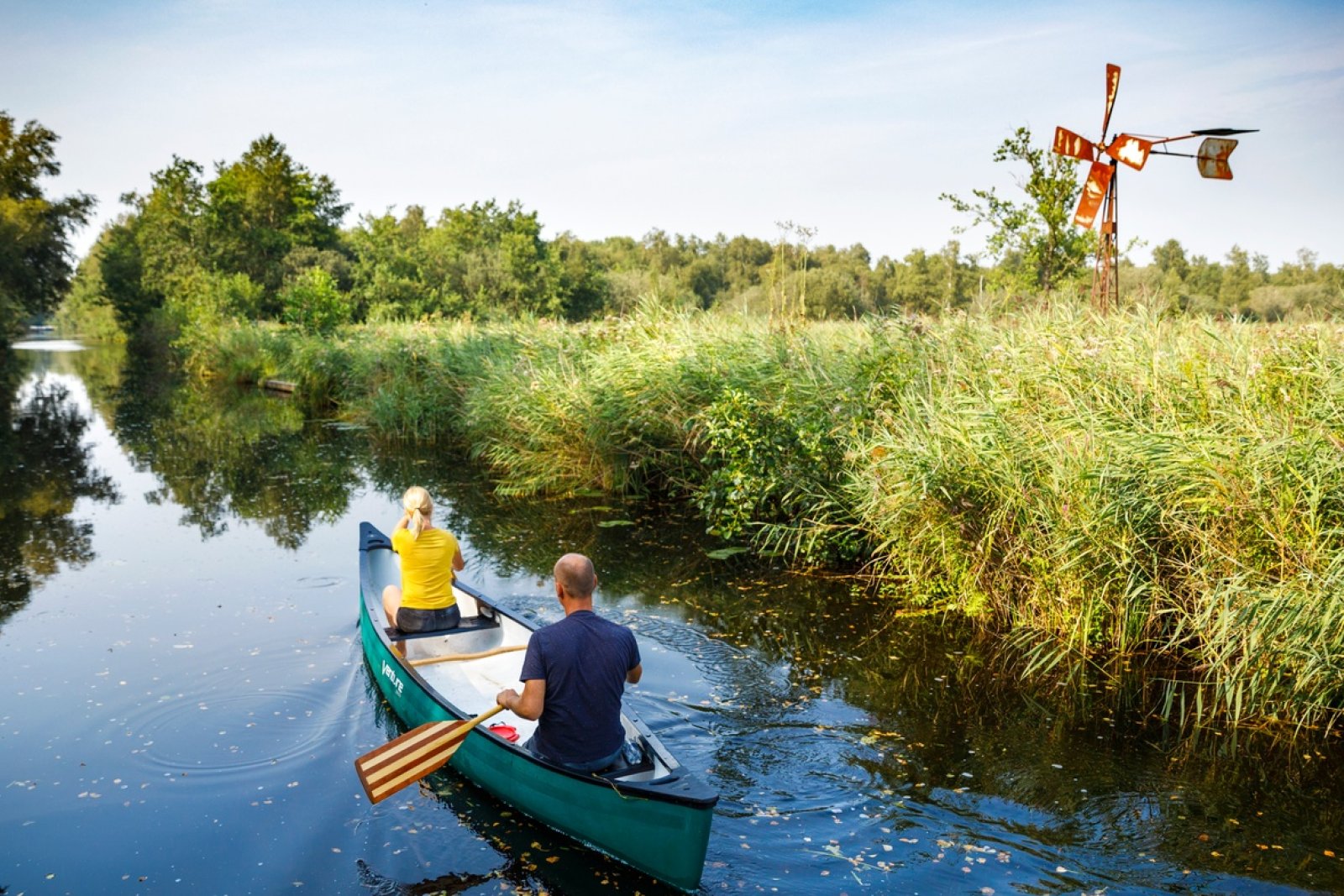 Canoeing past windmills and reed beds in National Park Weerribben-Wieden.