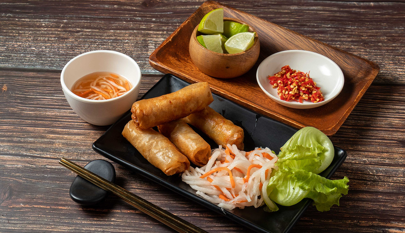 Fried spring rolls with lime and noodles served in bowl isolated on table top view Fried spring rolls with lime and noodles served in bowl isolated on table top view