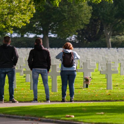 Group people stand still at the graves of the cemetery in Margraten