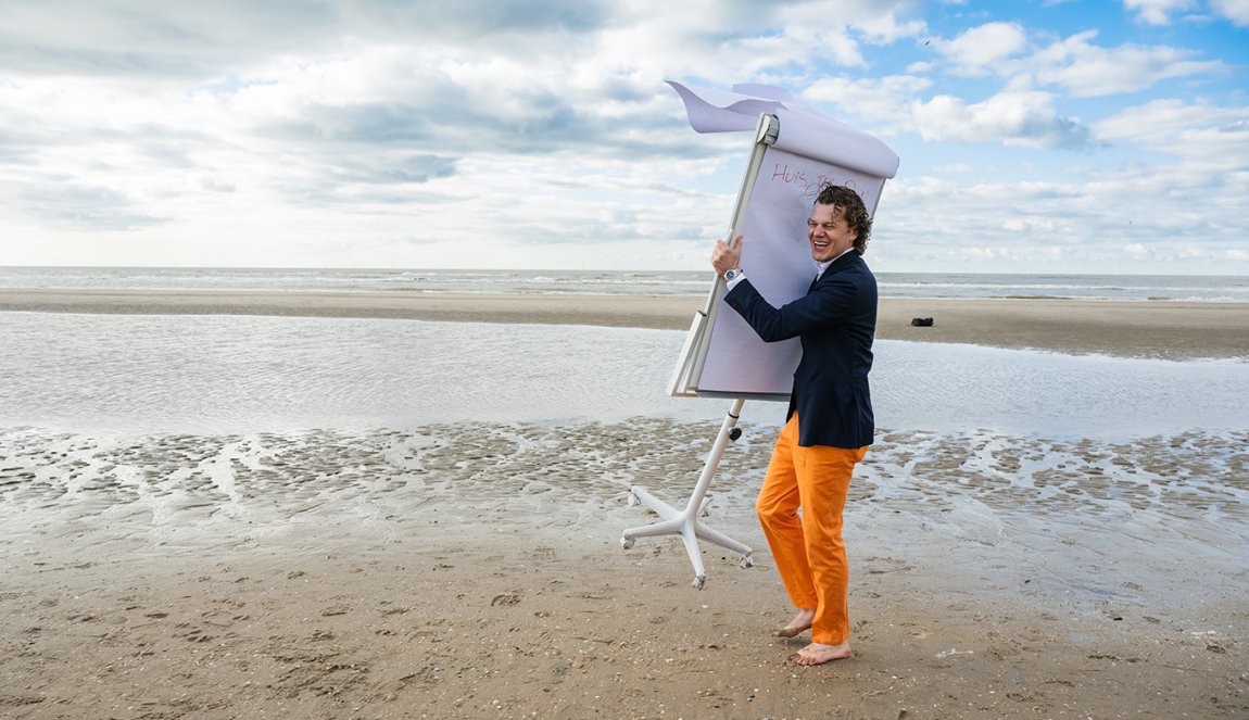 Portrait Coen van Veen on the beach with flipchart