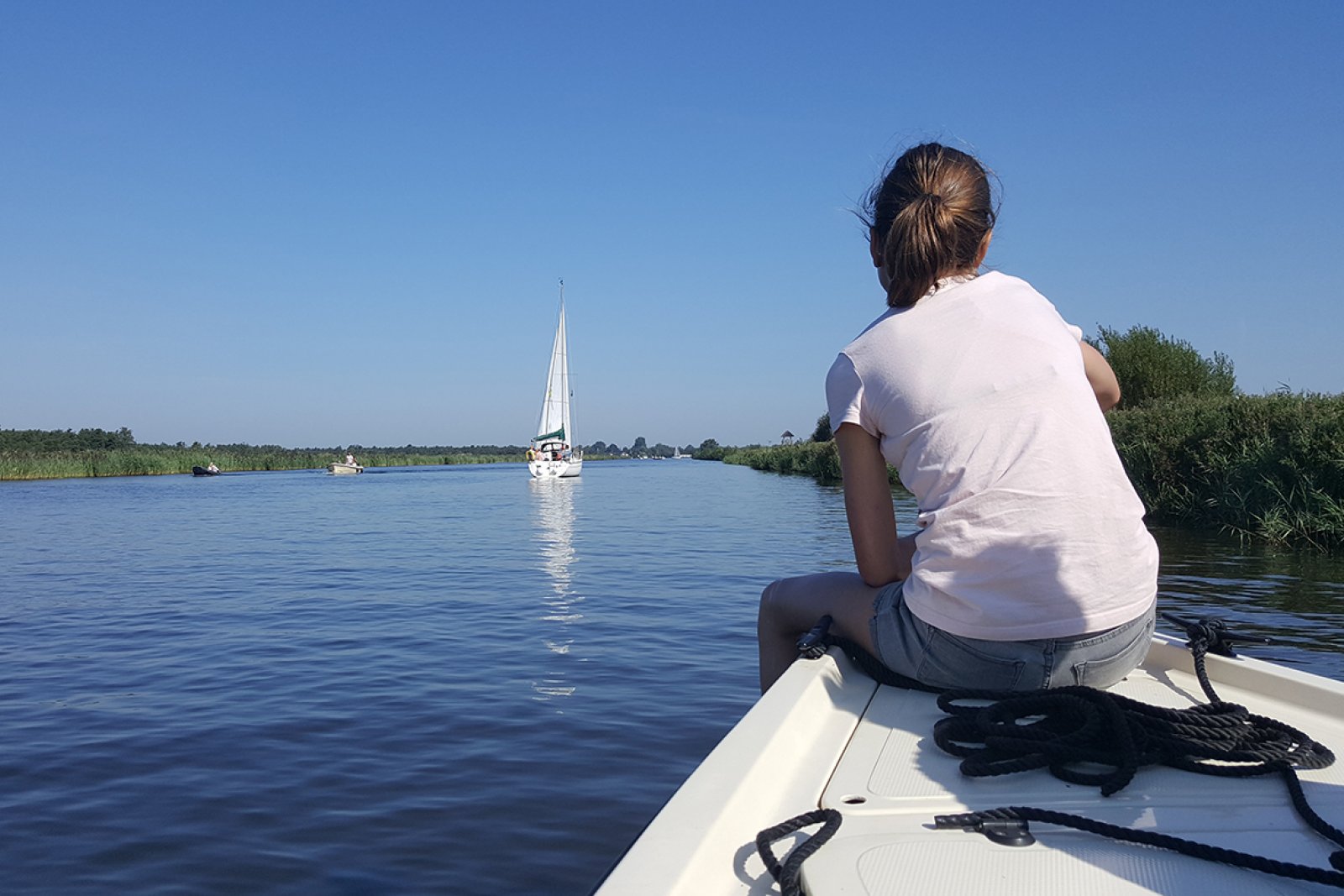 girl sitting on the edge of the boat looking at the Alde Feanen and the boats