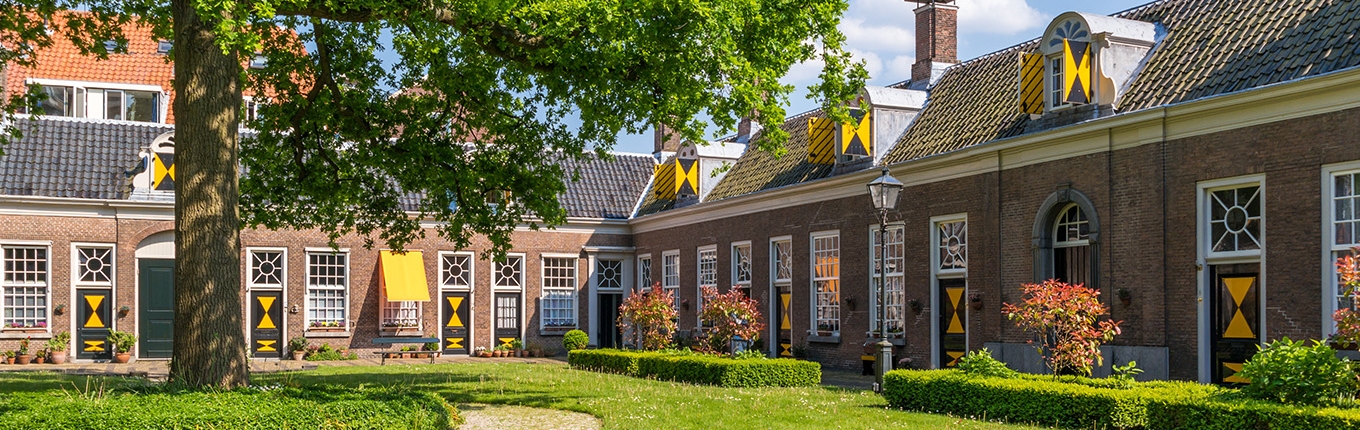 Green courtyard surrounded by old almshouses in Hofje van Staats in city of Haarlem