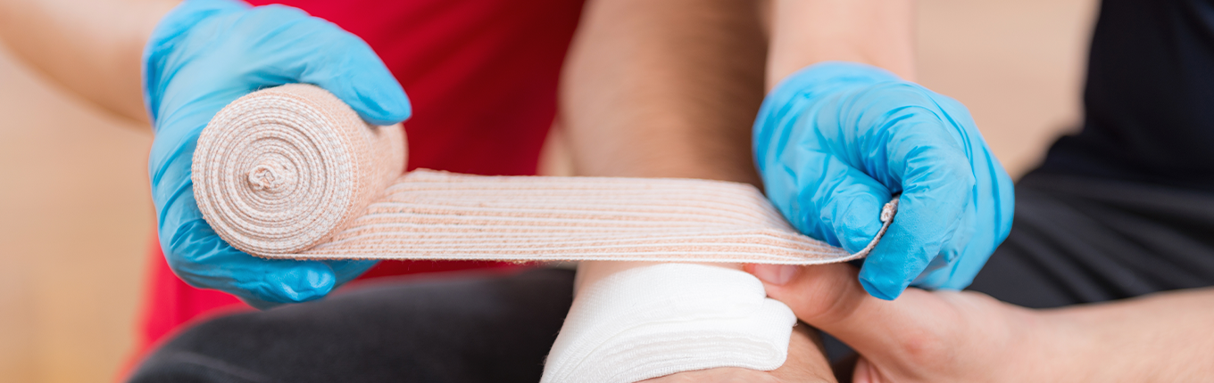 First aid training: blue gloves hand bandaging 