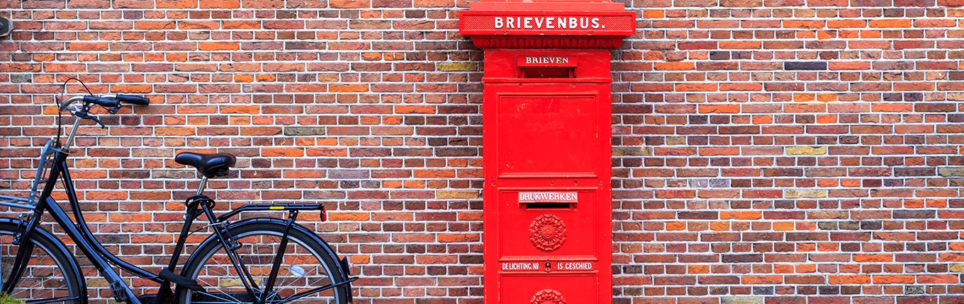 Big red vintage mailbox (brievenbus) against a brick wall