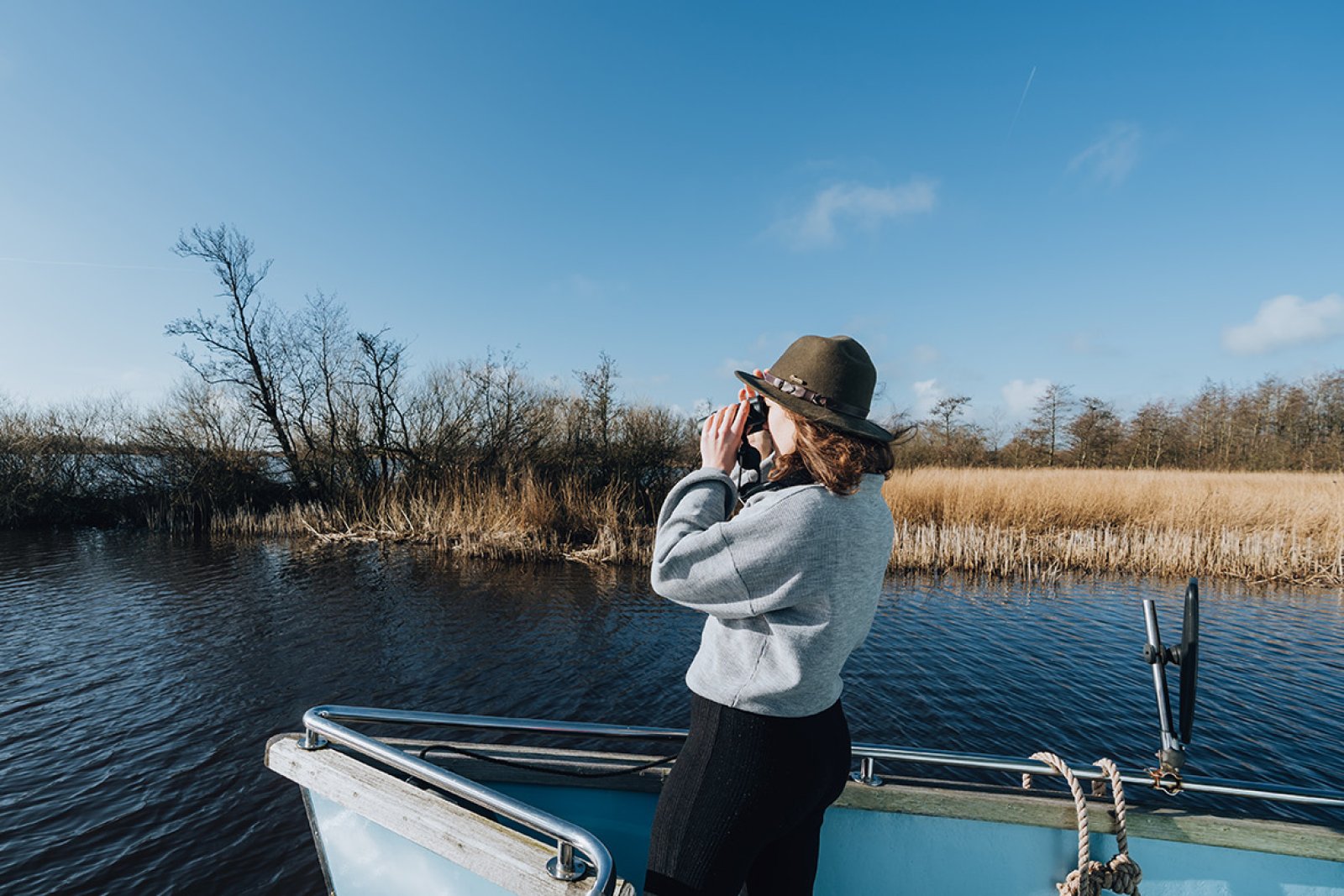 Girl on a boat sailing through the Alde Feanen while looking through a binocular