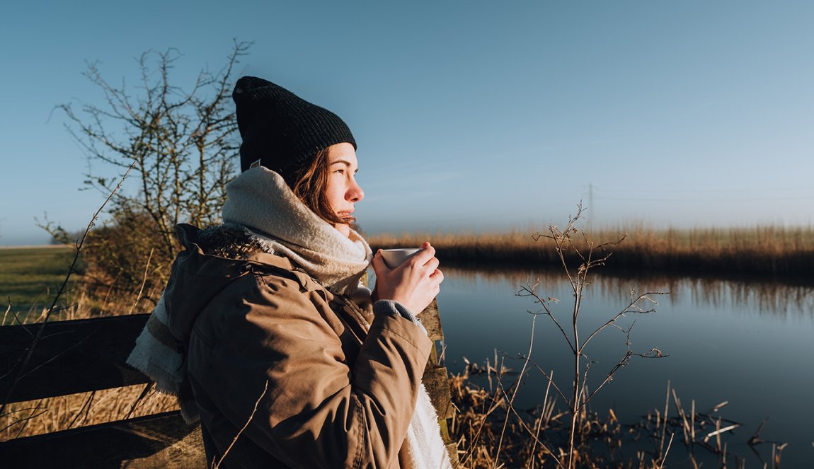 Winter in Friesland, Alde Faenen. Woman drinks coffee and looks over puddle