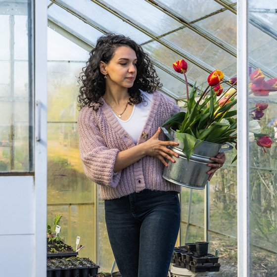 Lady in greenhouse with tulips in bucket 