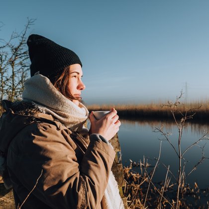 Winter in Friesland, Alde Faenen. Woman drinks coffee and looks over puddle