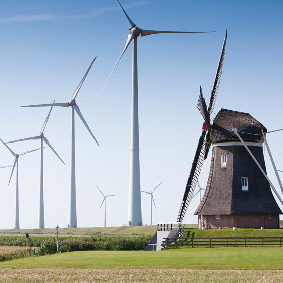 Traditional wind mill surrounded by wind turbines