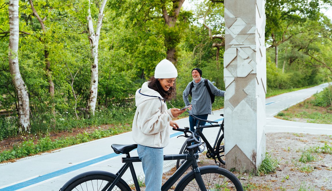 Cyclist checks bike app on phone Cyclist checks bike app on phone