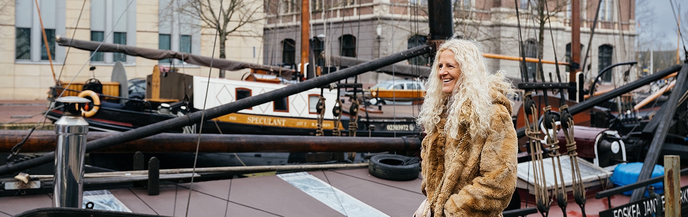 Portrait of Herma van Keulen, she stands in front of a ship
