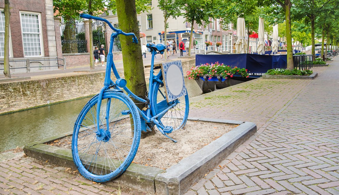 Old Dutch blue bicycle parked by a canal in Delft