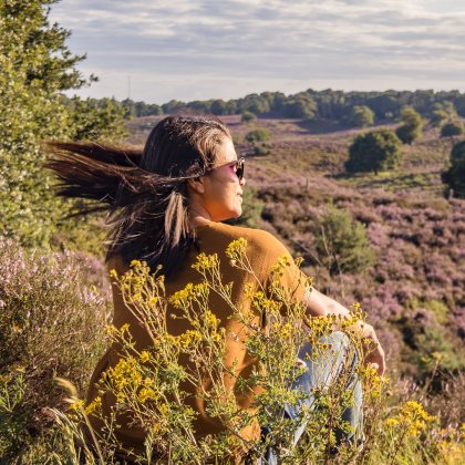 Girl sitting in grasfield looking at Nationalpark Veluwezoom 