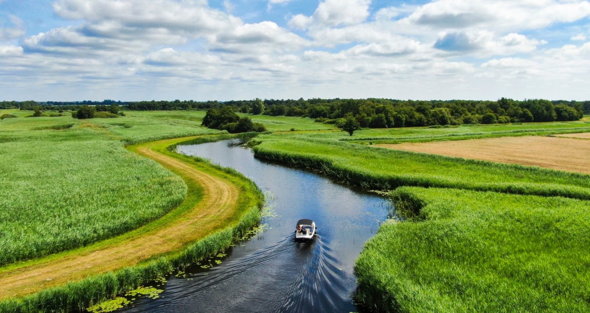 Boat sailing in water through Dutch landscape