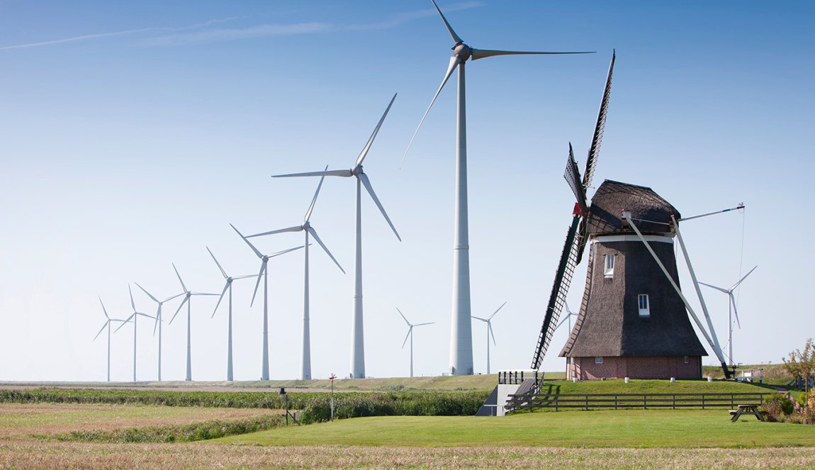 Traditional wind mill surrounded by wind turbines
