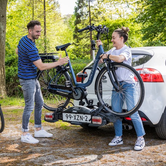 Young couple puts bikes on car's bike rack 
