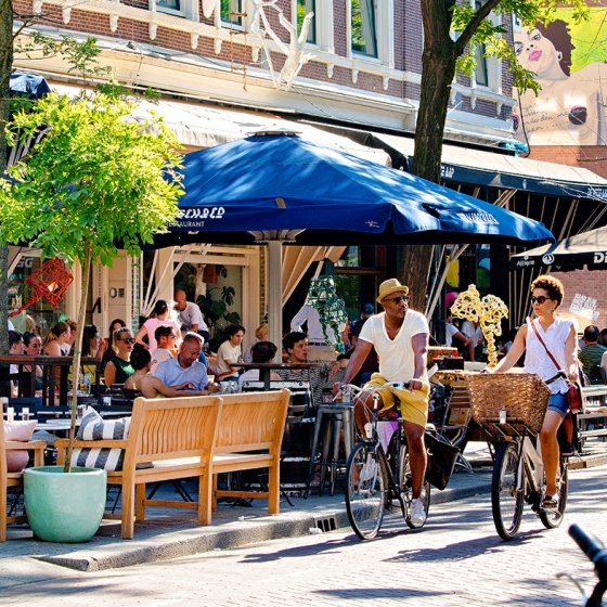 Couple cycling in summer through Witte de Withstraat Rotterdam