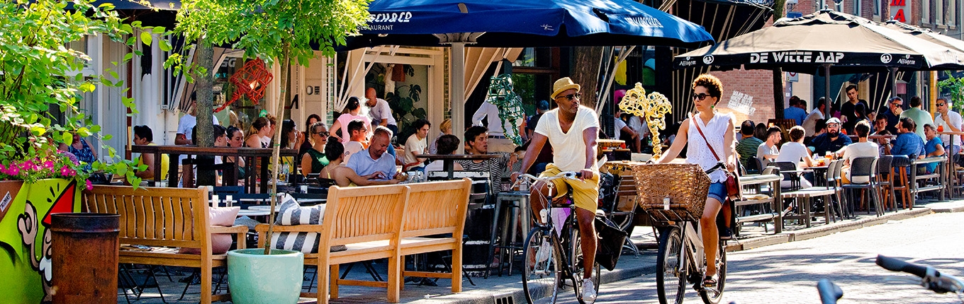 Couple cycling in summer through Witte de Withstraat Rotterdam Couple cycling in summer through Witte de Withstraat Rotterdam
