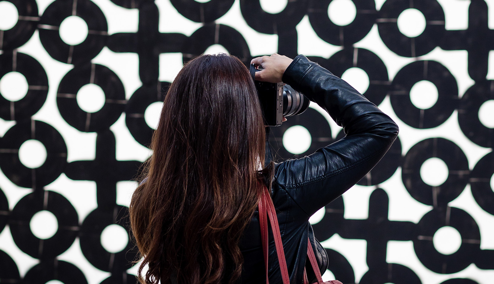 Woman takes photo in STRAAT museum with red bag Woman takes photo in STRAAT museum with red bag