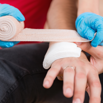 First aid training: blue gloves hand bandaging 