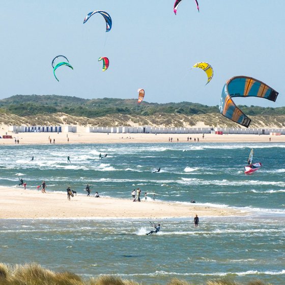 Kitesurfers at sea with beach and beach houses Vrouwenpolder Zeeland