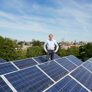 Portrait Robin Berg We Drive Solar standing on the roof with solar panels
