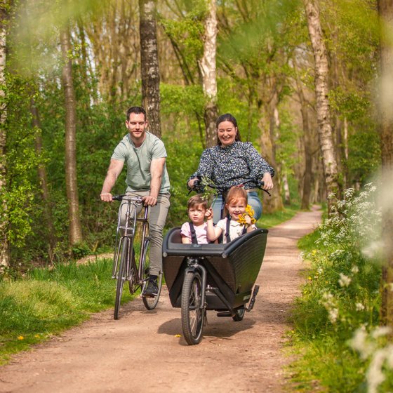 A family is cycling along the Ruthbeek in Enschede on a cargo bike